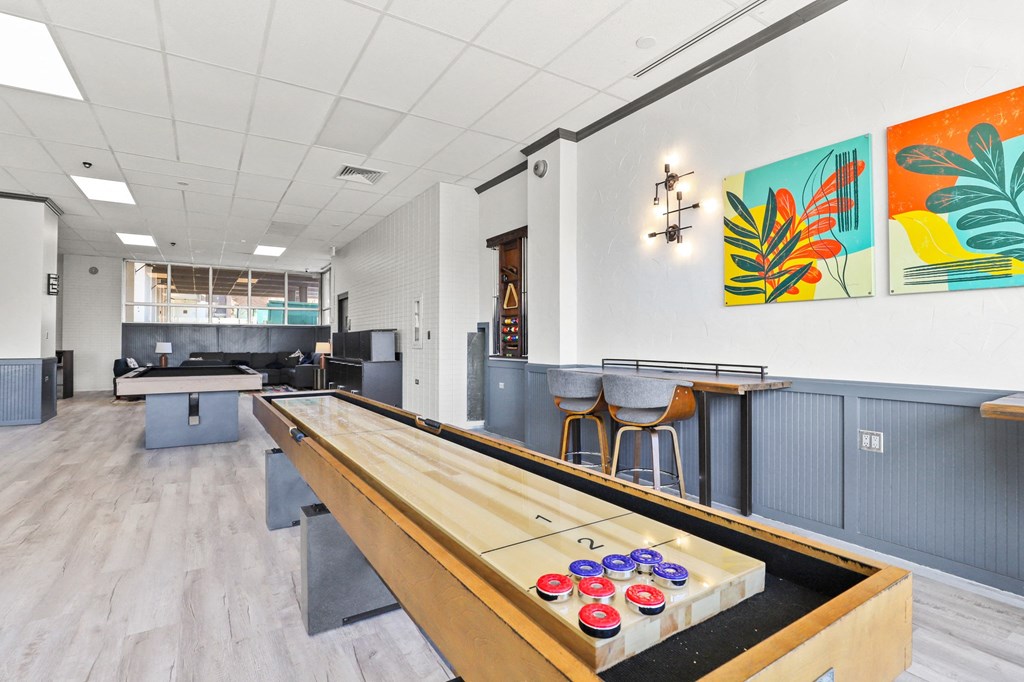 a game room with a shuffleboard table in the middle
