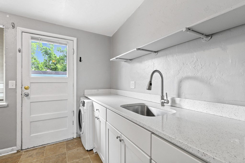 a kitchen with white cabinets and a white washer and dryer