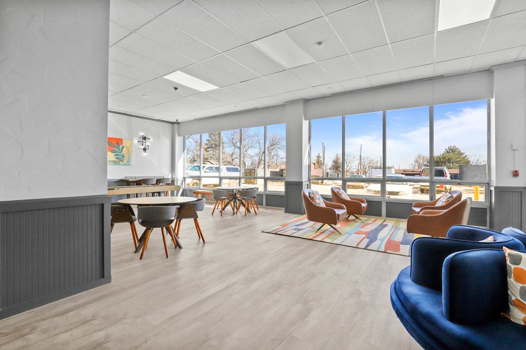 a living room with a table and chairs and large windows