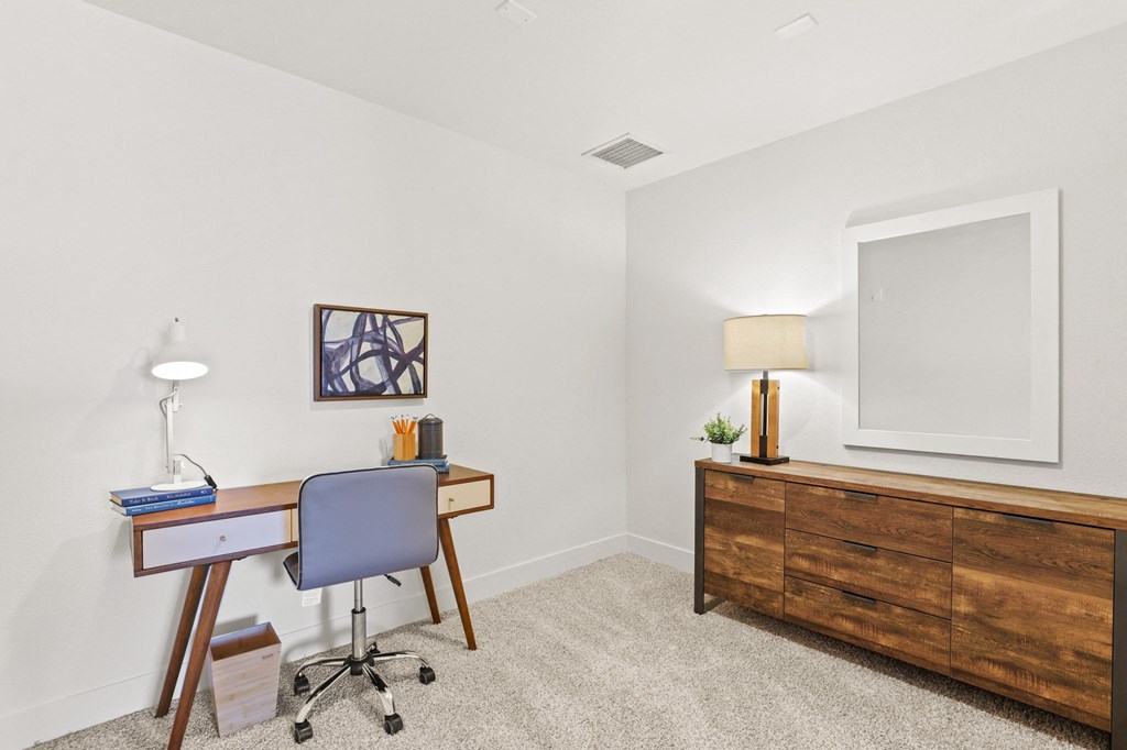 a bedroom with a desk and a dresser and a window