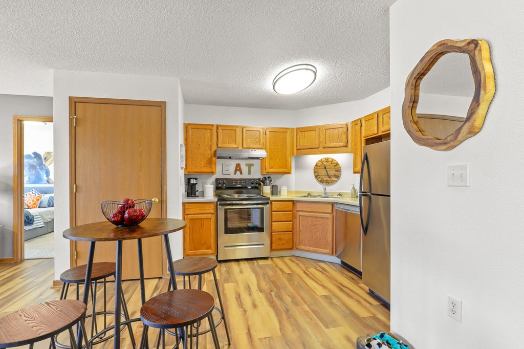 a kitchen with wooden cabinets and stainless steel appliances and a table with three stools