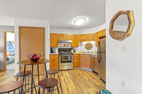 a kitchen with wooden cabinets and stainless steel appliances and a table with three stools