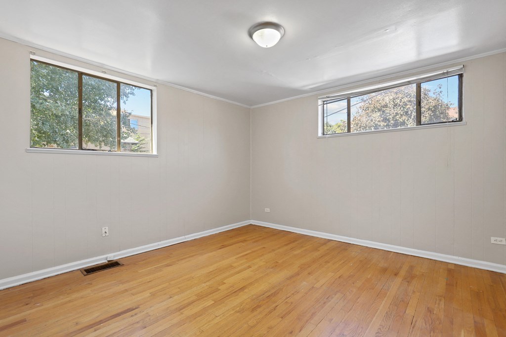 an empty room with wood floors and two windows