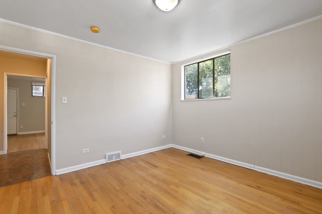 an empty living room with wooden floors and a window