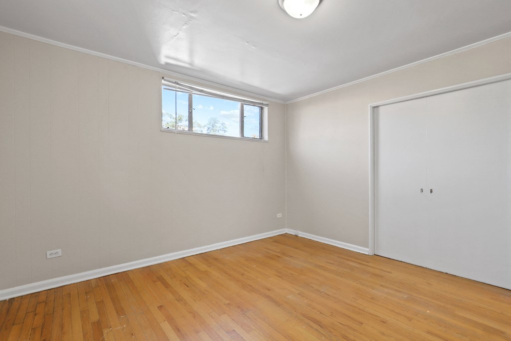 a living room with wood floors and white walls and a window