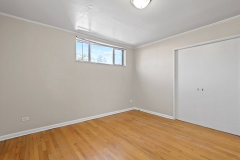 a living room with wood floors and white walls and a window