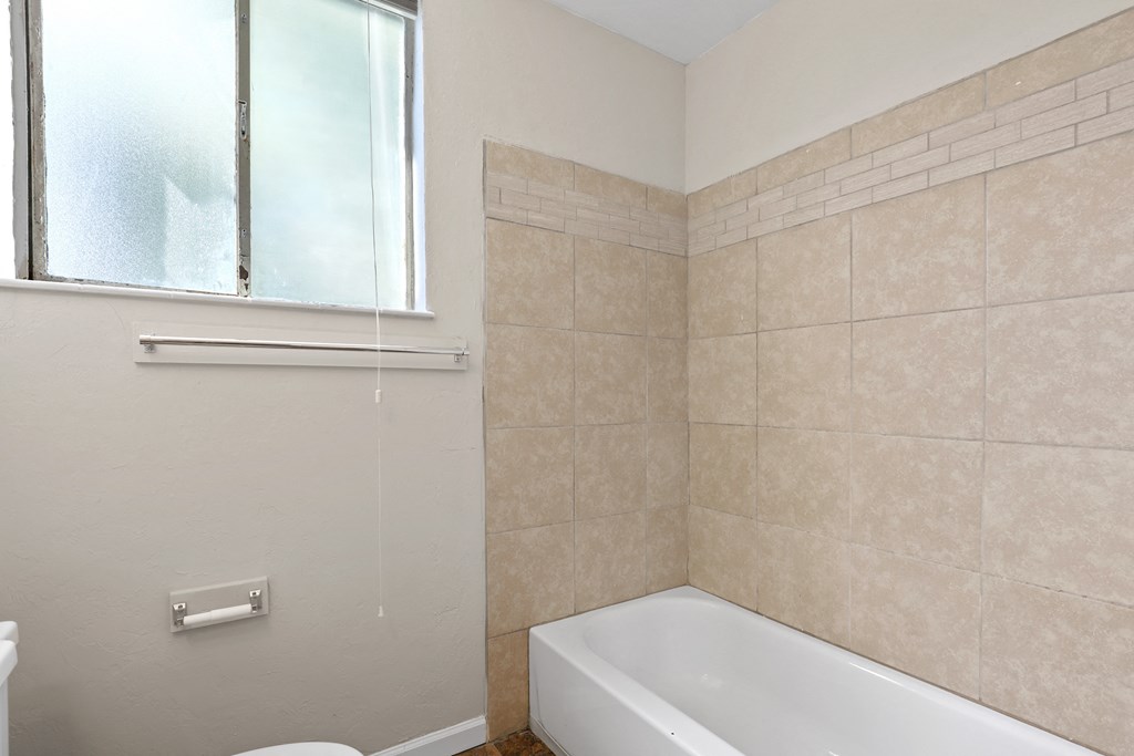 an empty bathroom with a tub and a window