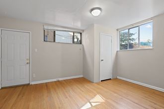 an empty living room with wooden floors and a white door and window