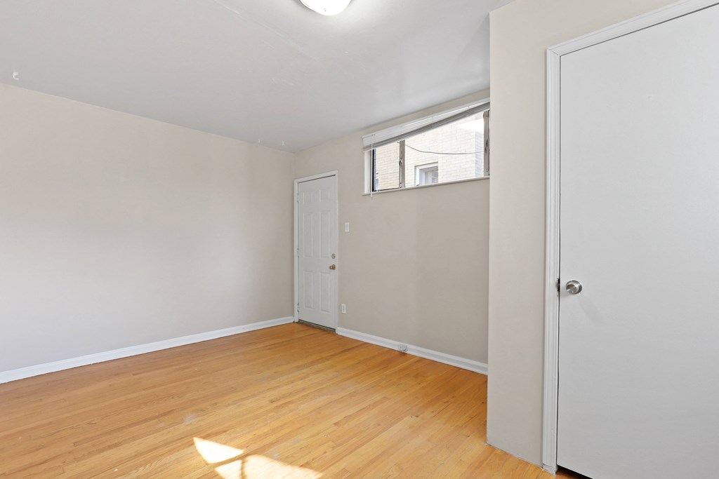an empty bedroom with wood flooring and a white door