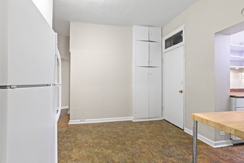 an empty kitchen with a refrigerator and a table
