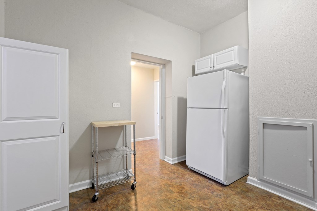 an empty room with two refrigerators and a cart