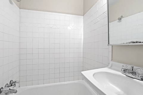 a white bathroom with a sink and a bath tub
