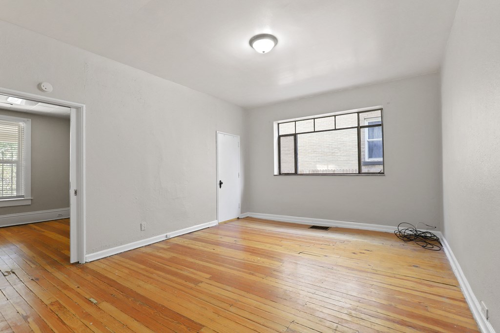 an empty living room with wood floors and a window