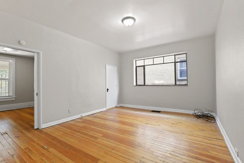 an empty living room with wood floors and a window