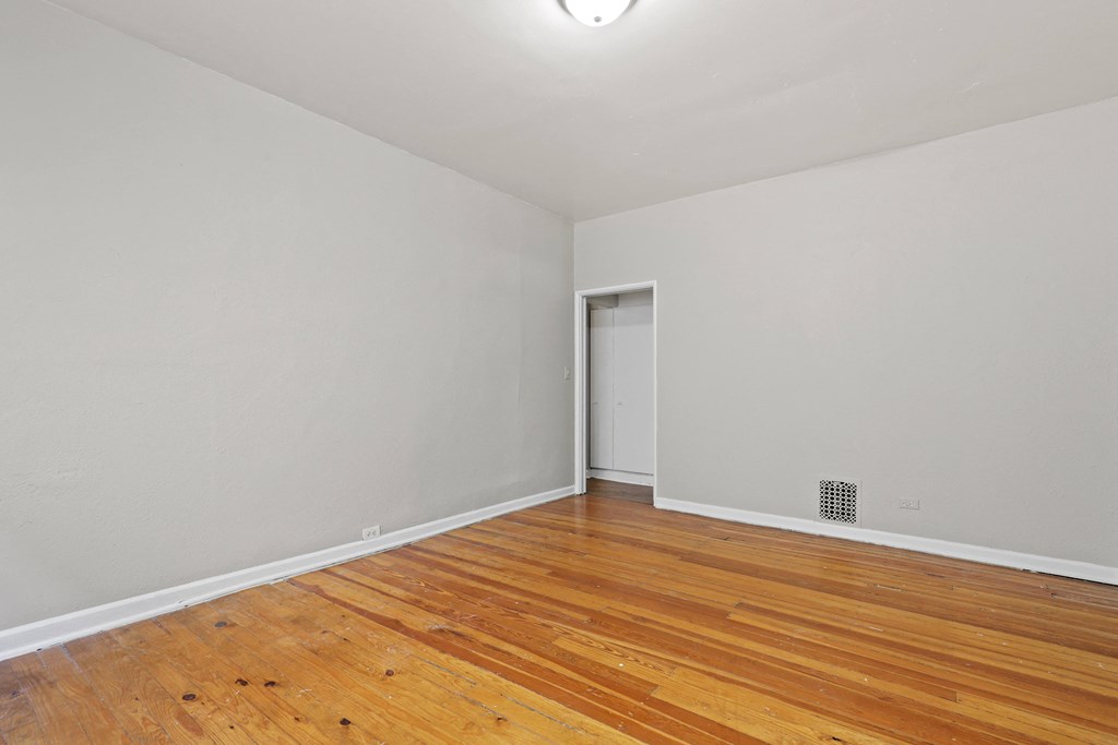 an empty room with wood flooring and white walls