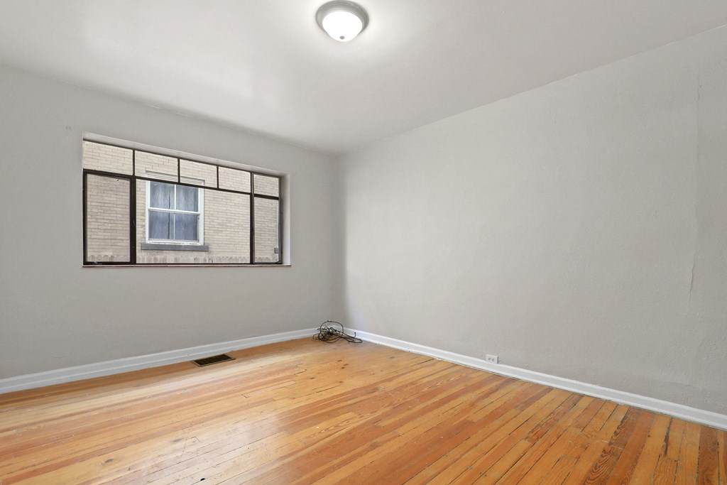 an empty room with wood floors and a window