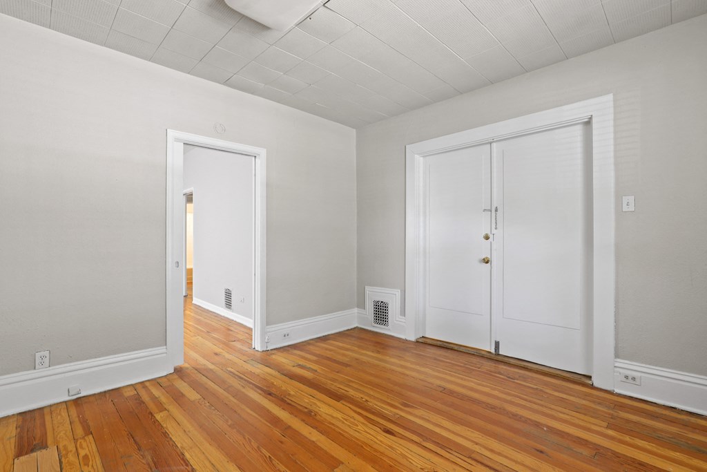 a living room with wood floors and white walls and two doors