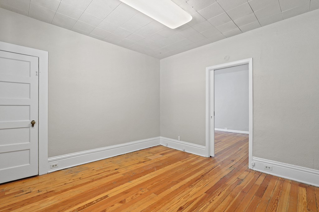 the living room of an empty house with wood floors and a white door