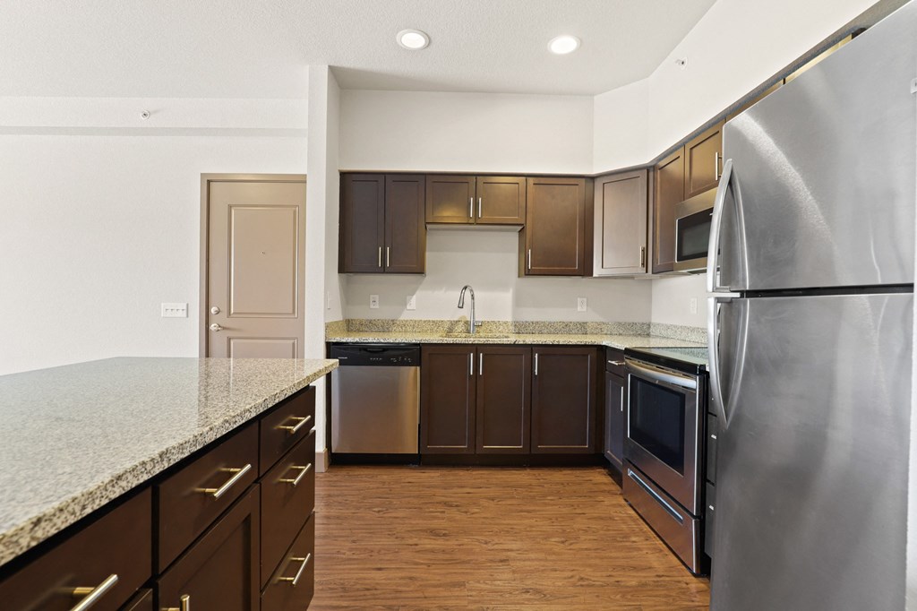 an empty kitchen with stainless steel appliances and granite counter tops