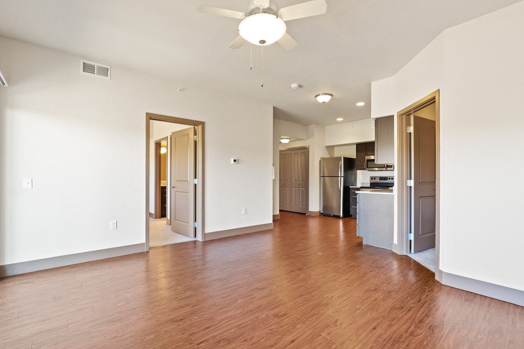 an empty living room with wood flooring and a ceiling fan