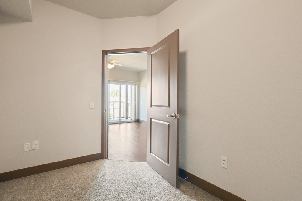 an empty room with a door open to a living room