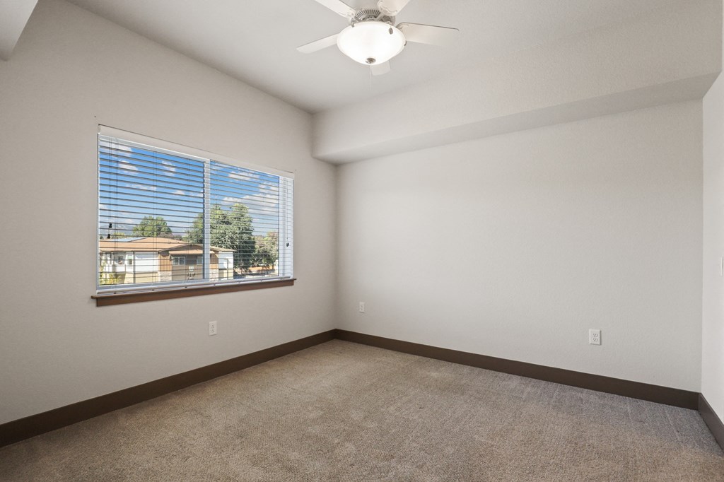 an empty living room with a window and a ceiling fan