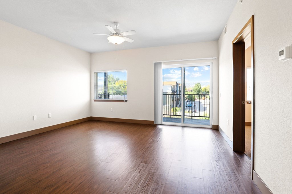 an empty living room with hard wood flooring and a balcony