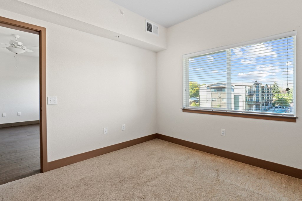 an empty room with a window and a carpeted floor