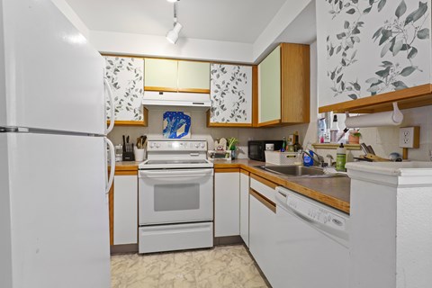 A kitchen with white appliances and wooden cabinets.