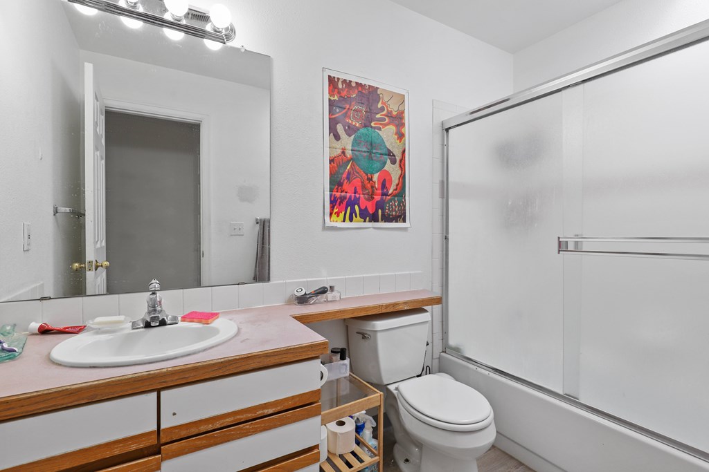 A bathroom with a toilet, sink, and a painting on the wall.