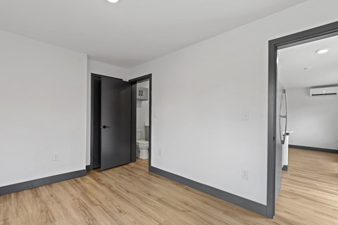 the living room of an apartment with white walls and hardwood floors