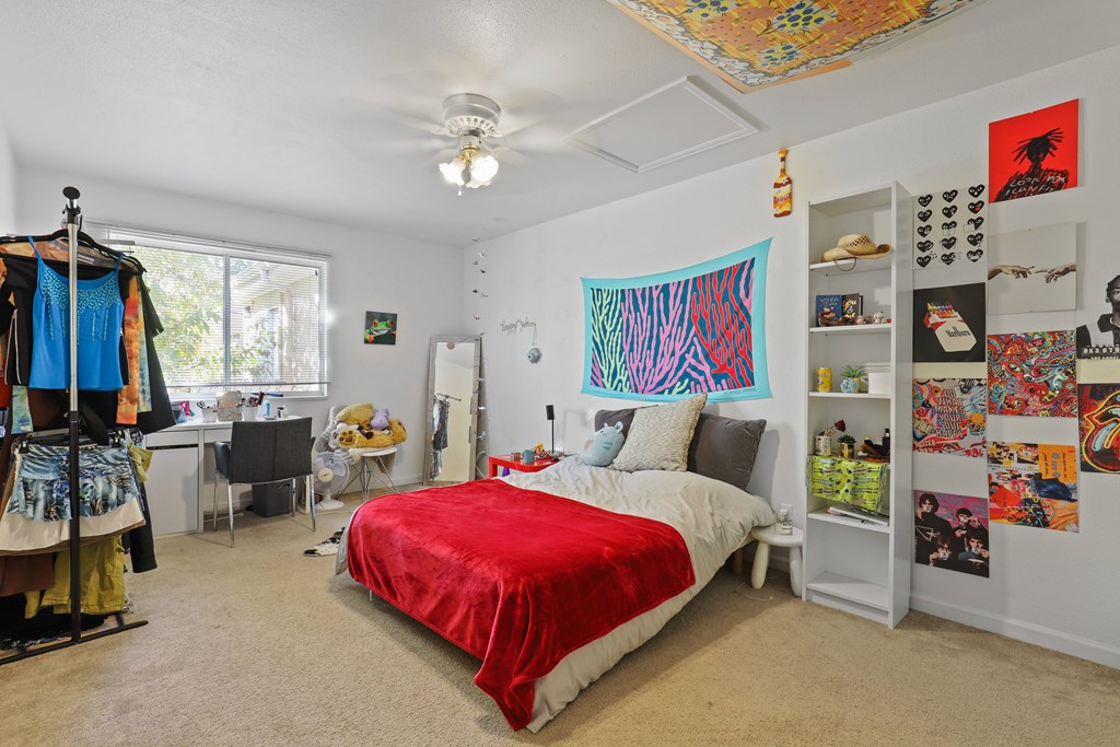 Bedroom with a red bedspread and a large artwork on the wall.