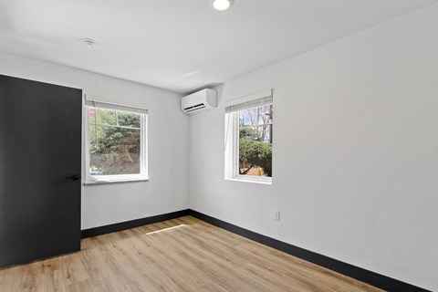 A room with a black door and a window with a view of trees.