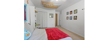 a bedroom with white walls and a red bed and a white closet