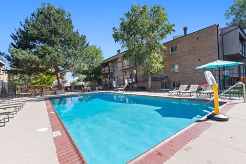 A swimming pool surrounded by trees and chairs.