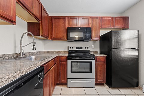 A kitchen with black appliances and wooden cabinets.