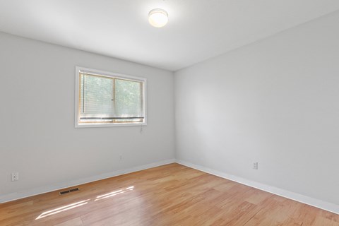 a bedroom with hardwood floors and a window