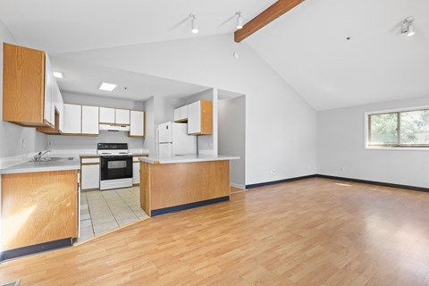 the living room and kitchen of a house with wood floors and white cabinets