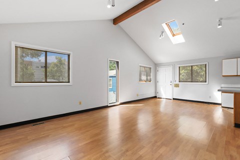 a spacious living room with hardwood floors and a vaulted ceiling
