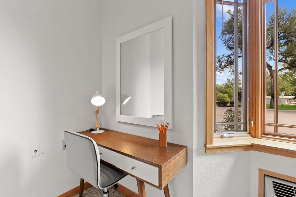 a home office with a desk and a large window