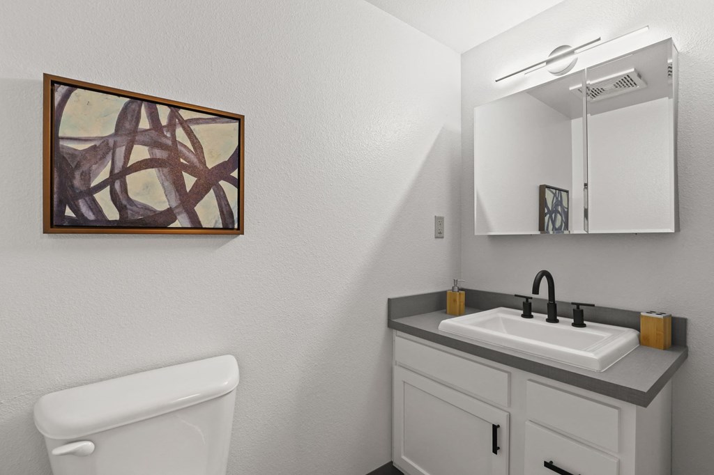 a bathroom with a toilet sink and mirror and a mirror on the wall