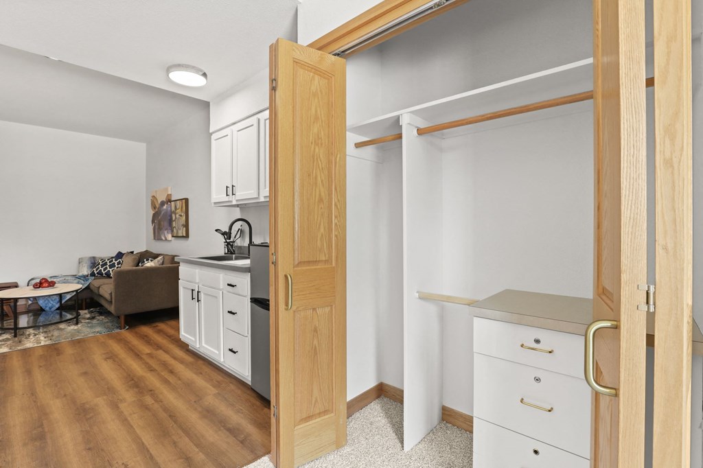 a kitchen with white cabinets and a door open to a living room
