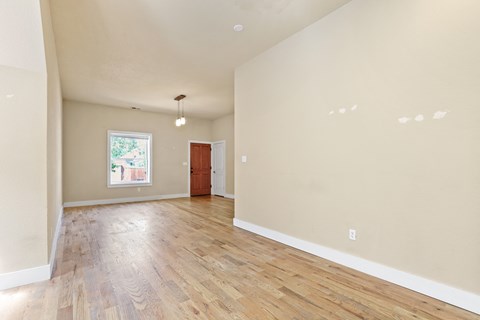 the spacious living room and dining room with hardwood floors and a window