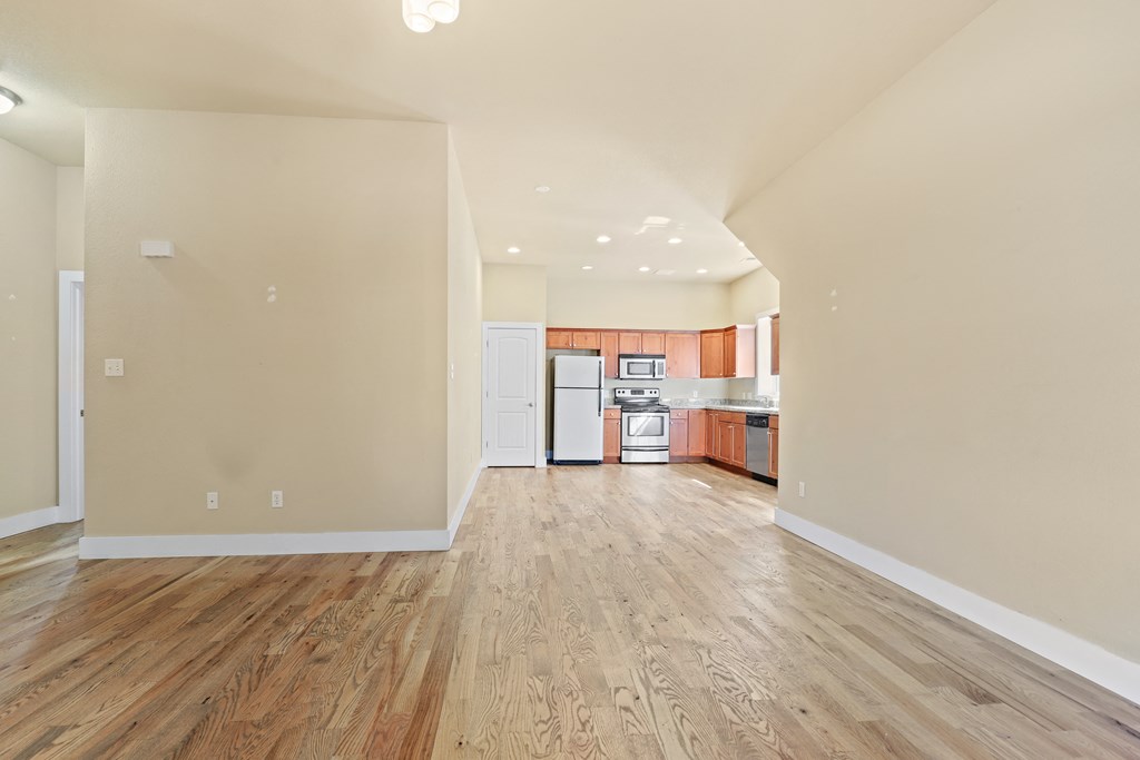 a living and kitchen area with hardwood floors and white walls