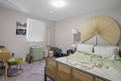 A bedroom with a bed, chair, and lamp.
