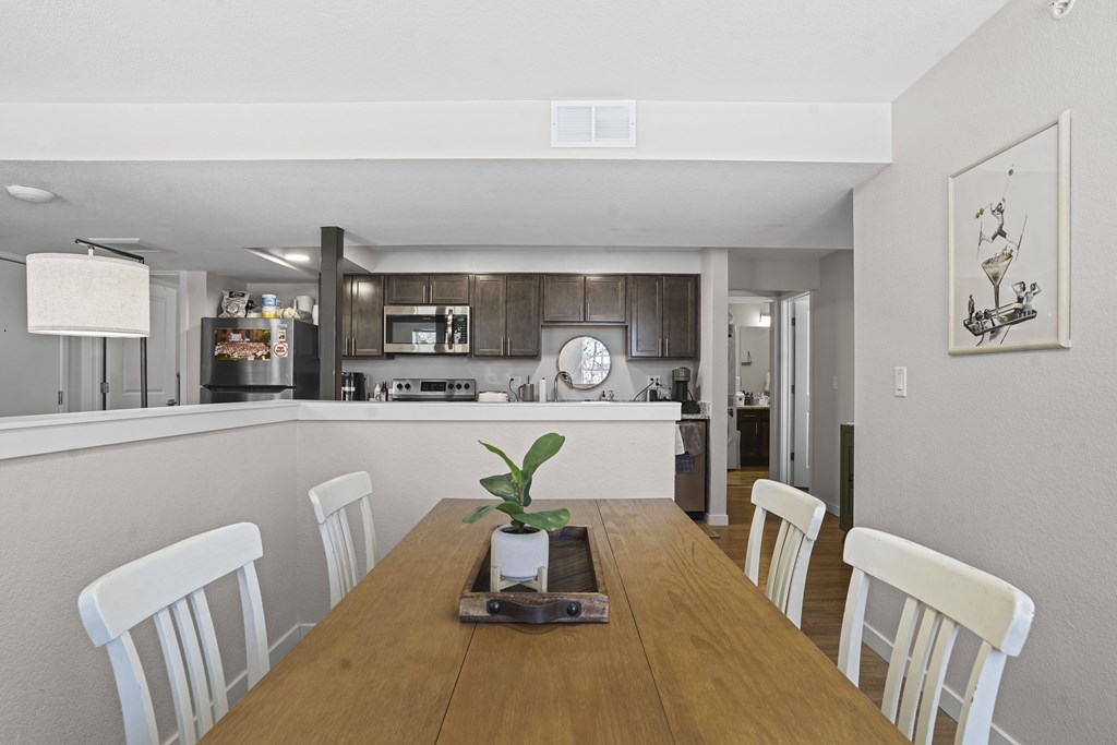 A dining room with a wooden table and white chairs.