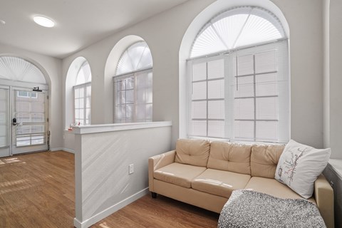 A living room with a tan couch and a large window.