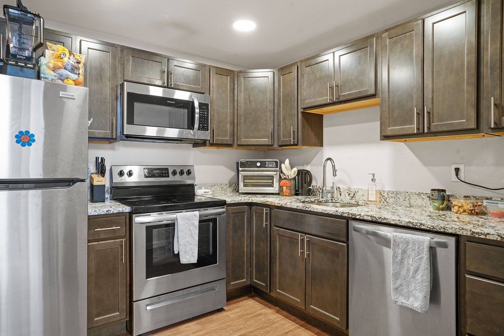 A kitchen with a stove, oven, refrigerator, and microwave.