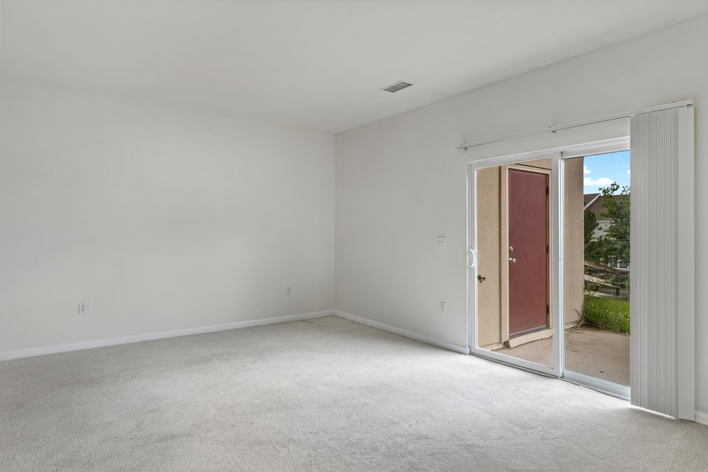A room with a carpeted floor and a door leading outside.