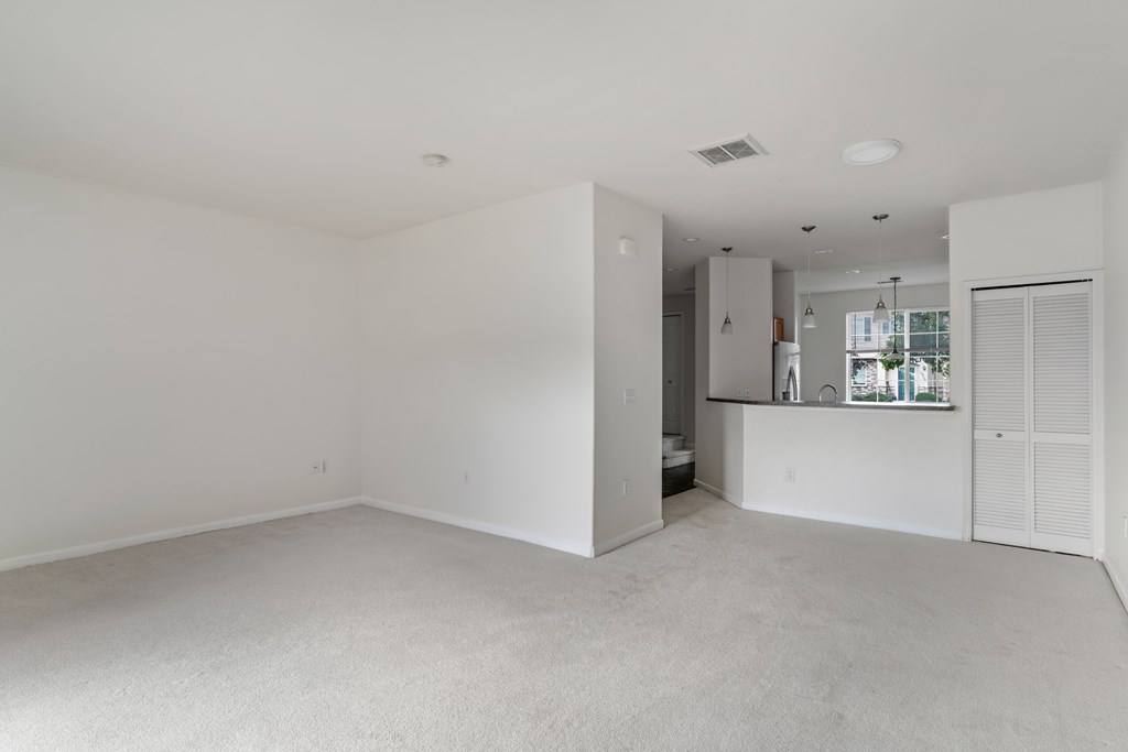 A large, empty room with white walls and carpeted floor.